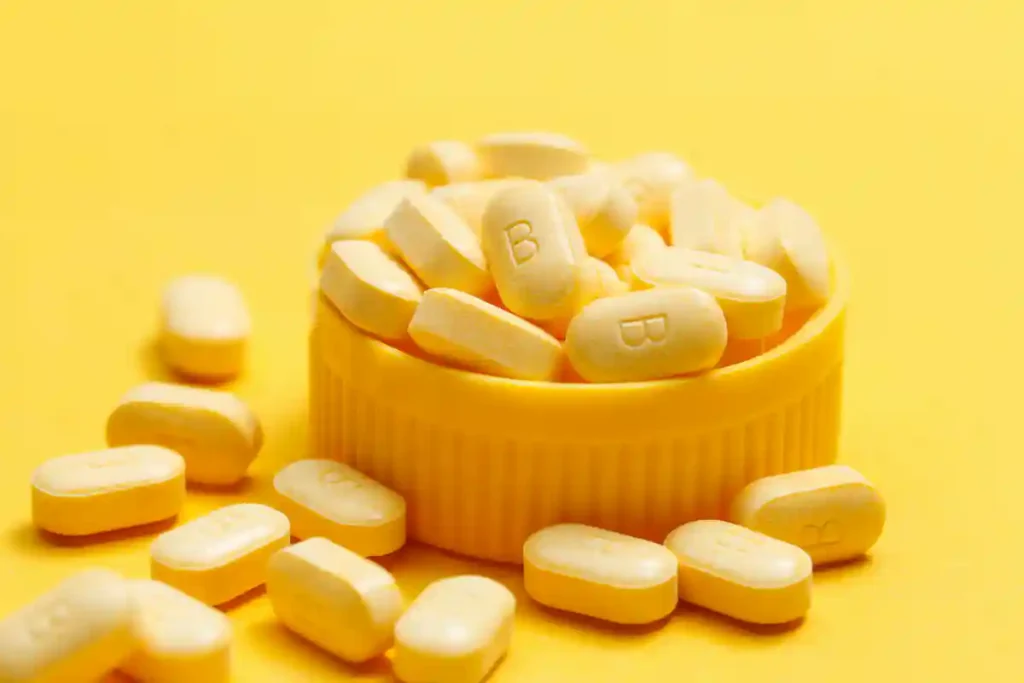Vitamin B12 tablets in a bowl on a yellow background representing deficiency and supplementation