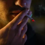 Close-up of a person smoking a cigarette, illustrating the importance of smoking cessation for COPD patients with reduced lung function and chronic respiratory symptoms.
